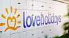 Loveholidays logotyp på en vit vägg med färgglad solsymbol.