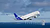 SAS-passagerarflygplan lyfter över havet med en rad vindkraftverk i bakgrunden.