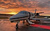 Ett privatjetplan står på en flygplatsplatta i skymningen.