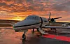 Ett privatjetplan står på en flygplatsplatta i skymningen.