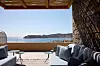 En modern terrass med loungemöbler, tak av trä och utsikt över havet och berg i fjärran.