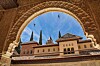 Alhambra i Granada ramas in av en ornately dekorerad båge mot blå himmel.