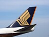 Bakre delen av ett Singapore Airlines-flygplan med guldfärgad logotyp mot blå himmel.