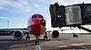 Ett Norwegian-flygplan står vid en gate på en flygplats med en passagerarbrygga framför.