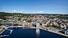 Flygvy över en kuststad med hamn, kajer, vatten och tätt bebyggt centrum.