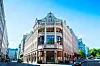 Ett stort historiskt hotell med ljus fasad och skylt mot gatan i centrala Oslo.