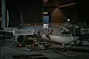 Ett passagerarplan från Qatar Airways står parkerat vid en gate i en upplyst flygplatsterminal.