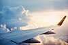 Utsikt från ett flygplansfönster över en vinge, moln och solnedgång.