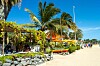 Palmkantad strandpromenad med kaféer, parasoller och några människor som går längs sanden i Santa Maria, Kap Verde, Afrika.