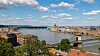 Donaufloden rinner genom en Budapest med broar, byggnader och molnig himmel.