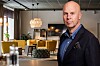 Bildmontage av Bellboy Hotels vd Johan Michelson i förgrunden i Hotel Kramms moderna hotelllounge med soffgrupp, lampor och stora fönster.