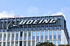Boeing-logga på toppen av en modern glas- och metallbyggnad mot blå himmel.