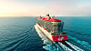 Det stora kryssningsfartyget Lady Valiant från Virgin Voyages seglar på havet under klar himmel.