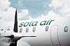 Ett vitt passagerarflygplan med grön Sola Air-logotyp mot en ljus himmel.