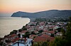 Vy över en kuststad med hus med röda tak, hav och berg i solnedgång. Lesbos, Grekland.