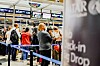 Resenärer står i kö med väskor vid incheckningsdiskar på en flygplats.