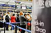 Resenärer står i kö med väskor vid incheckningsdiskar på en flygplats.