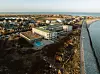 Ett stort hotellkomplex vid kusten intill stranden och havet under klar himmel.
