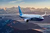 Ett Boeing 737 Max 7-flygplan flyger över berg i kvällsljus.