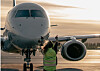 Ett passagerarplan på en flygplats med en person i reflexväst framför nosen.