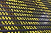 Gul text på en svart flyginformationstavla med flera destinationer och avgångstider.