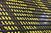 Gul text på en svart flyginformationstavla med flera destinationer och avgångstider.