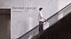 Person med resväska åker rulltrappa framför en vägg märkt ”Revolut Lounge – Coming soon”.