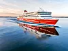 Ett rödvitt Viking Line-fartyg går på stilla vatten och speglas i havsytan.