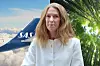 Kvinna i vit jacka framför ett SAS-flygplan och grönskande träd.
