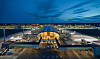 Oslo Lufthavn Gardermoens terminal sedd från luften i kvällsljus, med flygplan och taxibanor.
