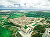 Flygbild över den muromgärdade staden Mdina på Malta, omgiven av gröna fält och vägar.
