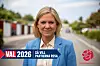 Kvinna i blå kavaj står på en väg med valgrafik och Socialdemokraternas logotyp.
