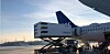 Ett SAS-flygplan står vid en flygplats medan en Newrest-lastbil lastar ombord catering.
