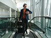 Resenär med kabinväska på rullband i en ljus och modern flygplatsterminal.