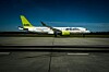 Ett airBaltic-flygplan taxar på en start- och landningsbana med ett annat flygplan i bakgrunden.