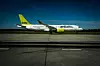 Ett airBaltic-flygplan taxar på en start- och landningsbana med ett annat flygplan i bakgrunden.