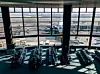 Flygplatsterminal med sittplatser och flygplan synliga genom stora fönster.