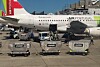 Ett TAP Air Portugal-flygplan står på en flygplats med bagagevagnar framför.