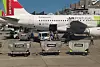 Ett TAP Air Portugal-flygplan står på en flygplats med bagagevagnar framför.