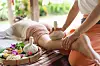 Massage med örtkompress på en person som ligger på en bädd utomhus.