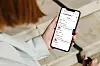 Person i ljus jacka håller en smartphone med en lista över reseinformation.