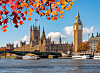 Big Ben och parlamentsbyggnaden vid Themsen, med Westminster Bridge och höstlöv i förgrunden.