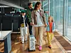 En grupp resenärer går genom en ljus flygterminal med kabinväskor.