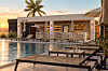 Hotellpool med solstolar och palmer i varmt kvällsljus.