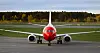 Ett rödvitt Norwegianflygplan står framifrån på en asfalterad flygplatsyta.